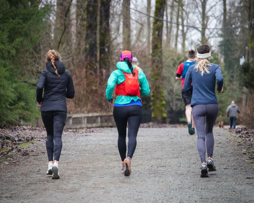 A diverse group of runners jogging together on a park path, smiling and engaged in conversation during a social run
